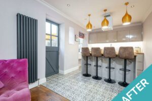 a photo of our east cottage property let after making holiday home improvements open plan kitchen with gold lights, a bar with stools, and pink chair
